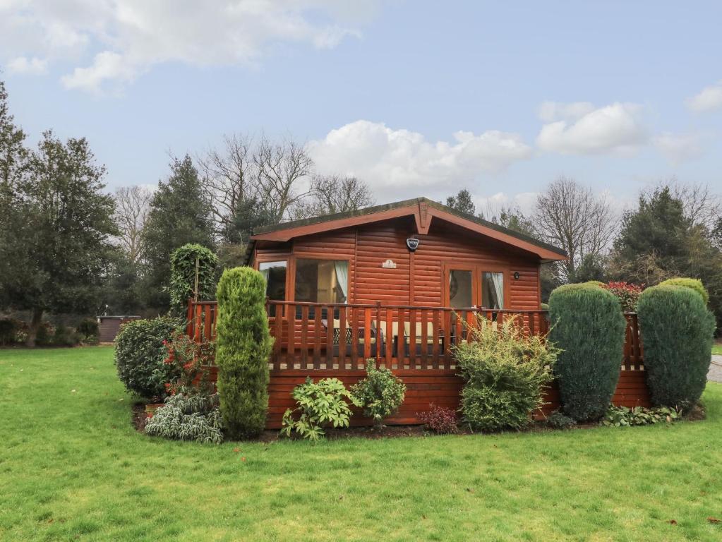 a log cabin in a yard with bushes at 3 The Fairway in Cottingham