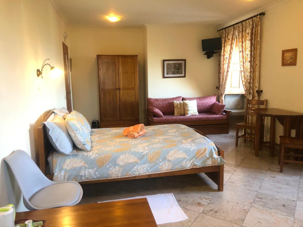 uma sala de estar com uma cama e um sof em Quinta das Cegonhas em Gouveia