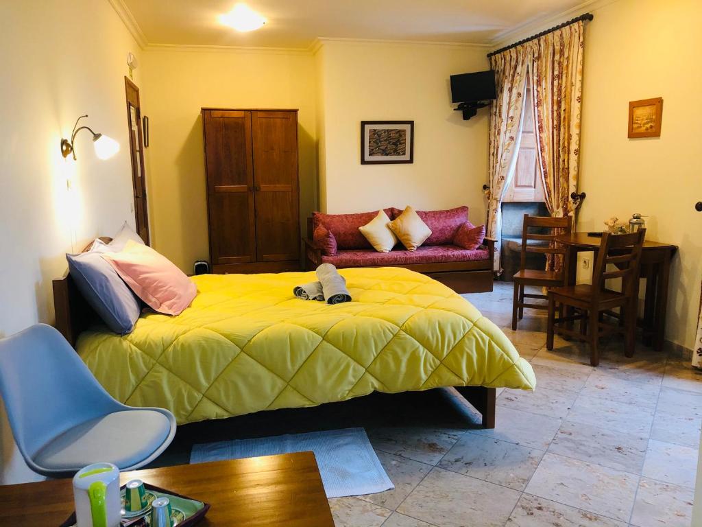 um quarto com uma cama amarela e um sof em Quinta das Cegonhas em Gouveia