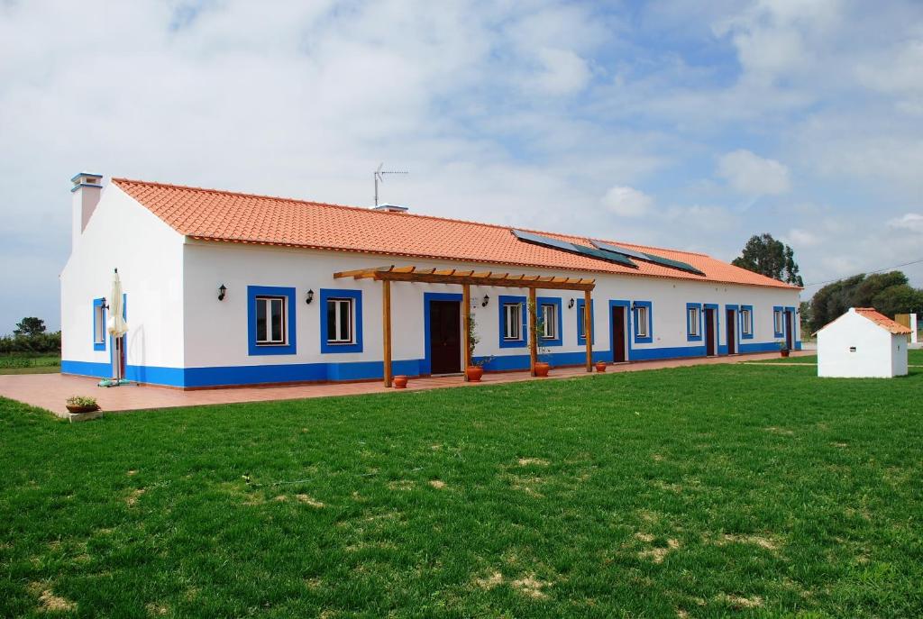 ein Haus mit einem grünen Feld davor in der Unterkunft O Monte da Estrada in Zambujeira do Mar