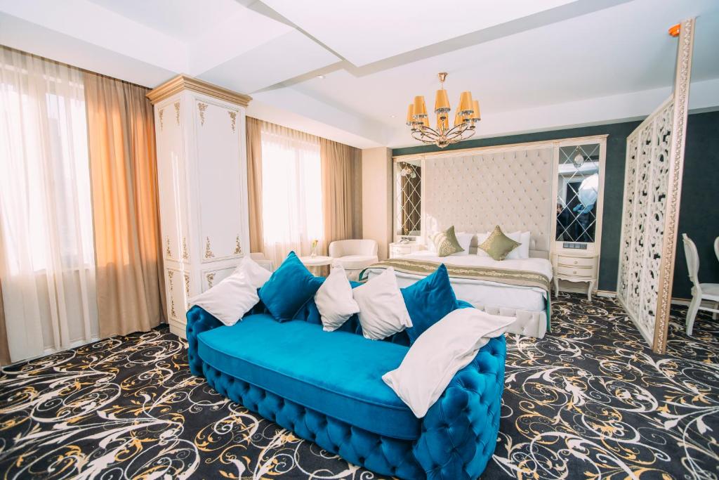 a hotel room with a blue couch and a bed at Gold Tbilisi Hotel in Tbilisi City