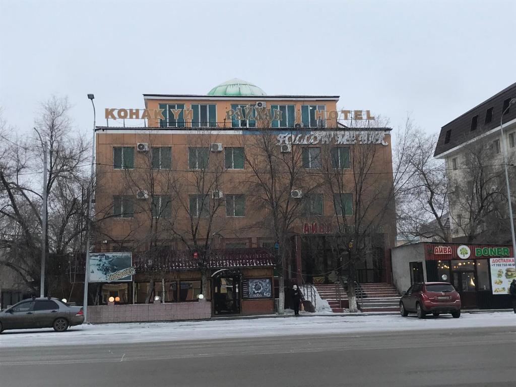 a building with a sign on top of it on a street at Гостиница Райхан in Atyrau