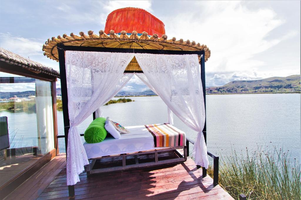 a bed on a deck next to a body of water at Uros Samaraña Uta Lodge in Puno