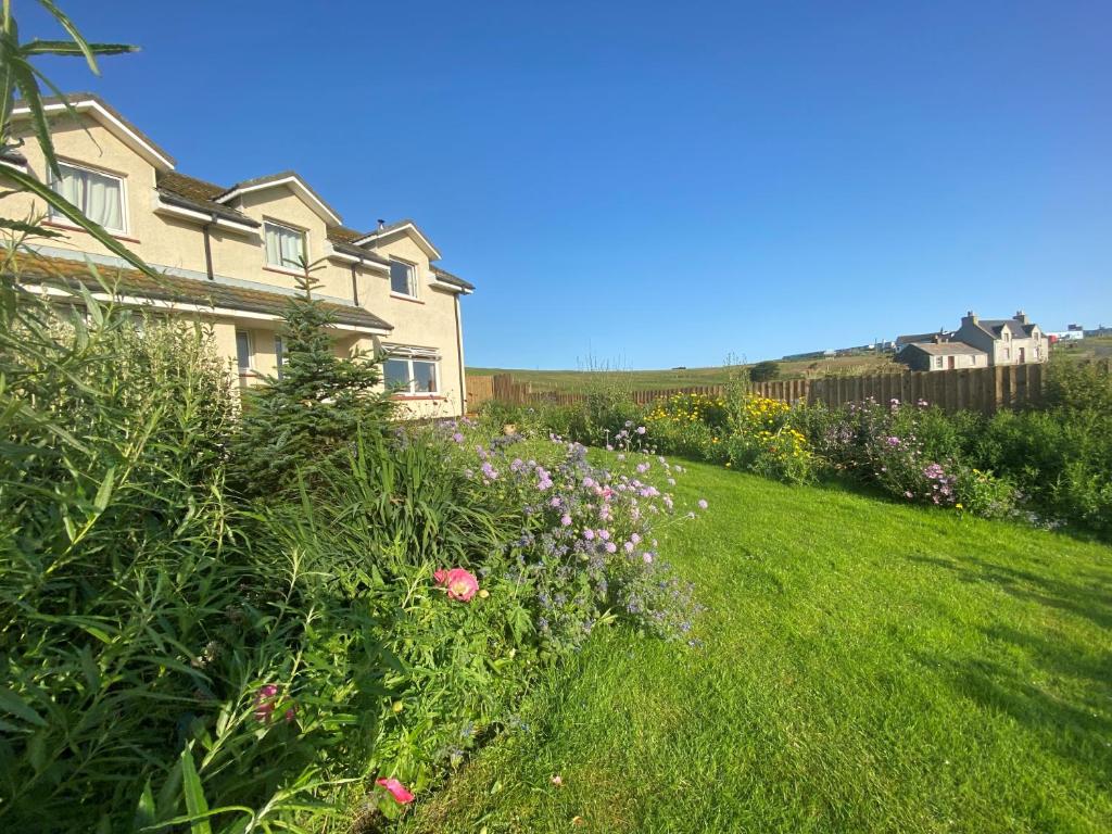 a grassy yard with a house and some flowers at SEAcroft Licensed B&B and Restaurant in Aird Uig