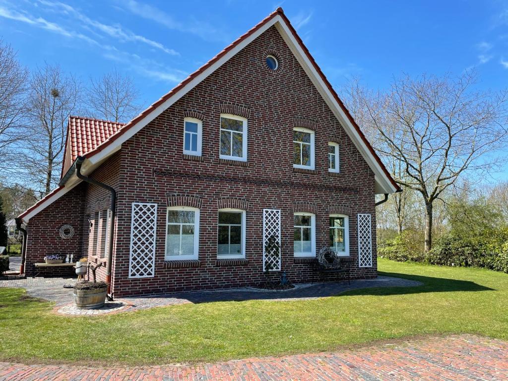 a large red brick house with a grass yard at Ferien-am-Uhlenmeer Keine-Monteure in Apen