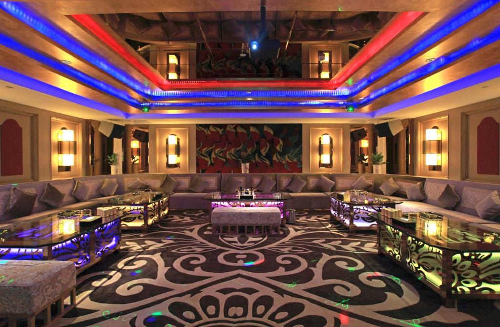 A dramatic lounge with wraparound sofas, low tables and vivid ceiling lighting.