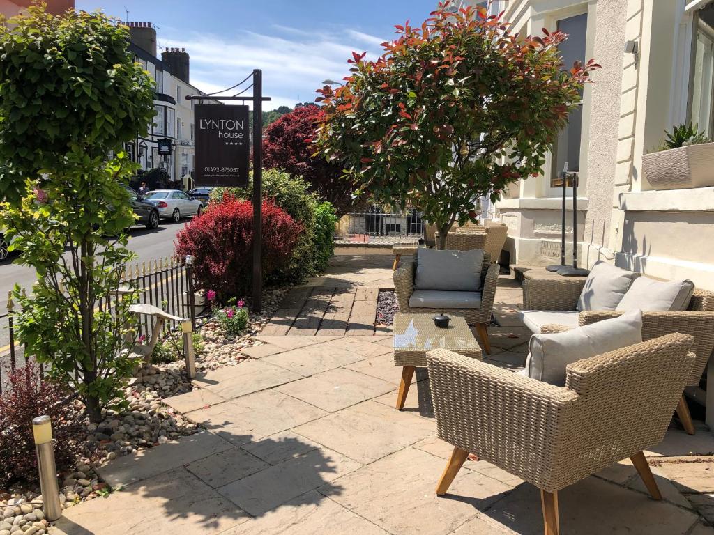 a patio with wicker chairs and chairs on a sidewalk at Lynton House in Llandudno