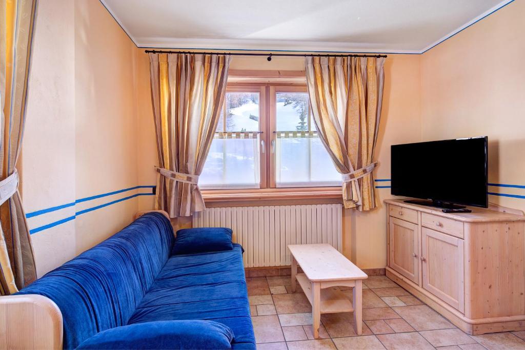 a living room with a blue couch and a tv at Chalet Betty Appartamento Sgembro in Livigno