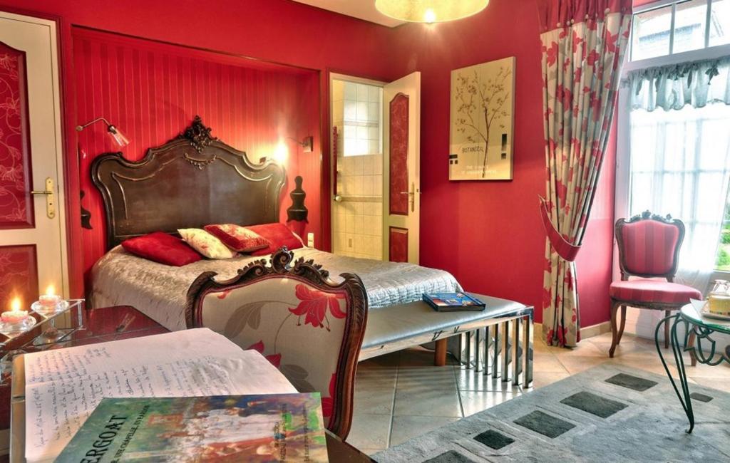 een slaapkamer met rode muren en een bed en een tafel bij Lanévry, Yseult in Kerlaz