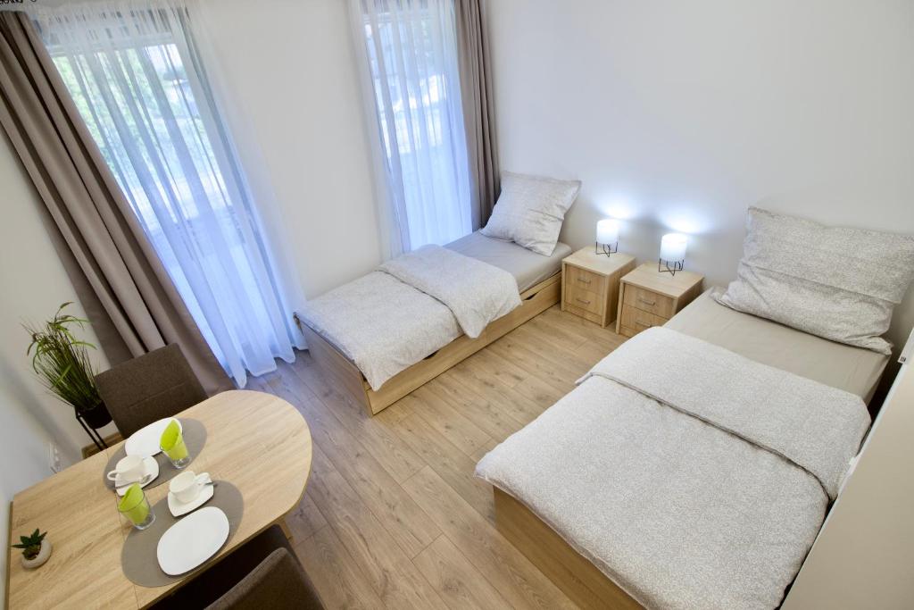 Sala de estar con 2 camas y mesa en Sport Centrum Apartman en Pápa