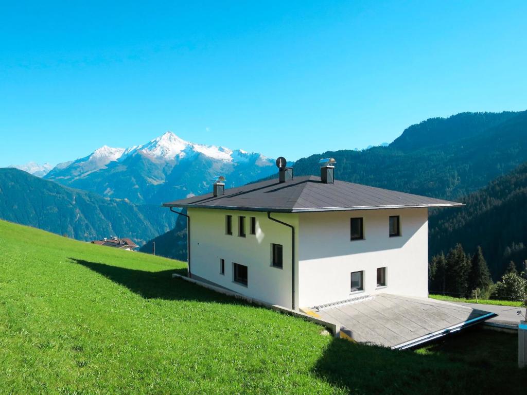 a house on a hill with mountains in the background at Apartment Schöser - MHO779 by Interhome in Hippach