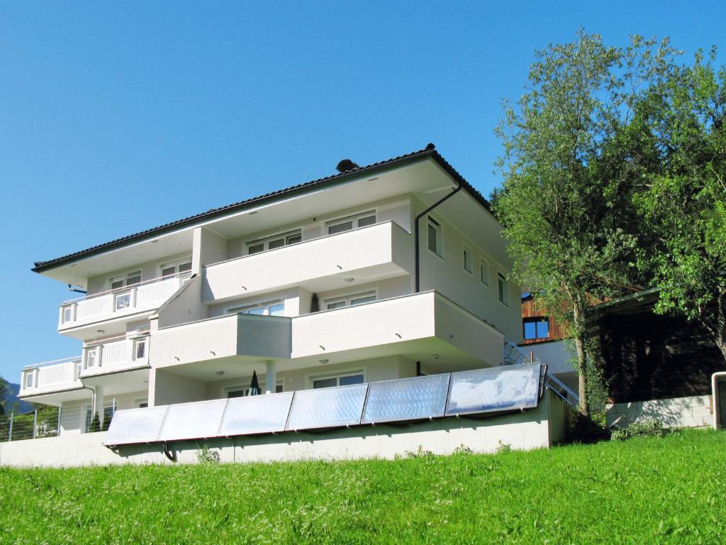 um edifício de apartamentos com varandas brancas e um campo verde em Apartment Hanser - MHO754 by Interhome em Ramsau im Zillertal