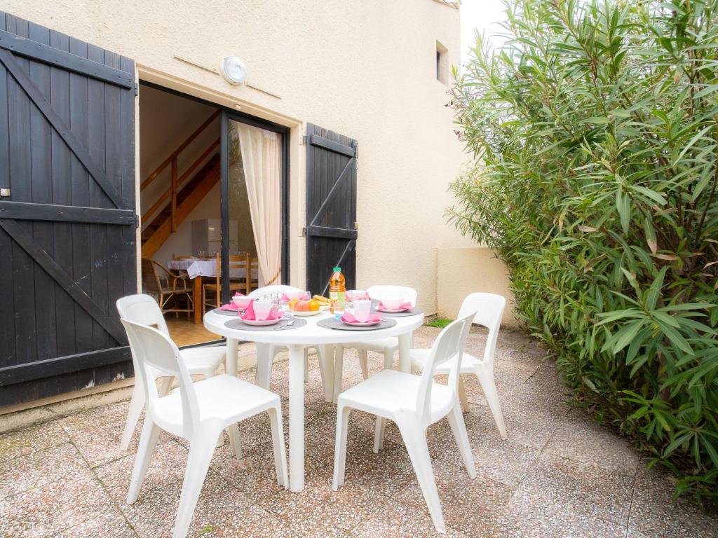 einen weißen Tisch mit weißen Stühlen und rosafarbenem Geschirr darauf in der Unterkunft Holiday Home Les Maisons de la Plage-8 by Interhome in Le Grau-du-Roi