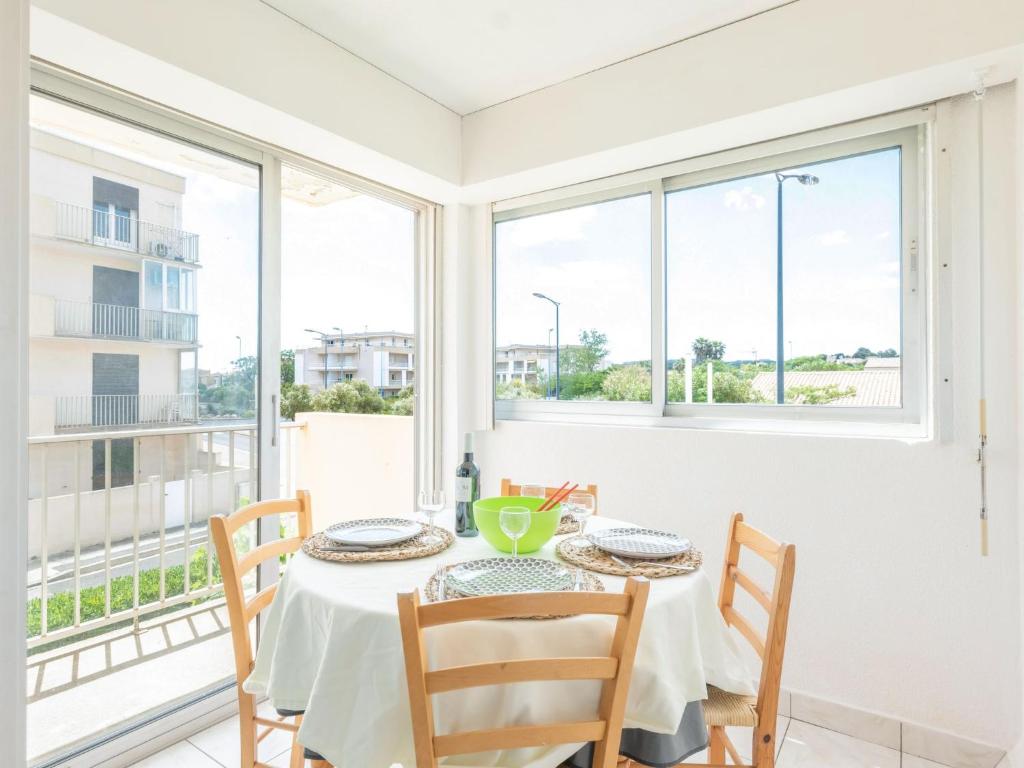 uma sala de jantar com mesa, cadeiras e janelas em Apartment La Méditerranée by Interhome em Narbonne-Plage