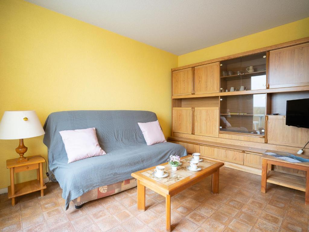 ein Wohnzimmer mit einem blauen Sofa und einem Tisch in der Unterkunft Apartment Les Sables d'Or-5 by Interhome in Le Grau-du-Roi