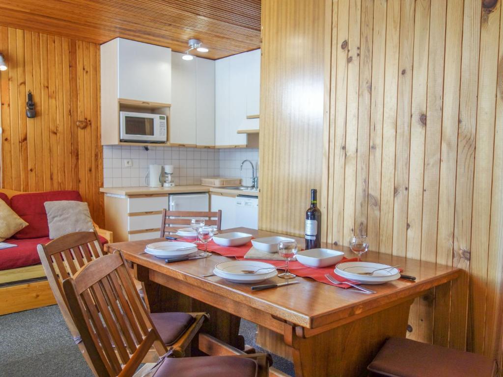 una cucina con tavolo in legno, piatti e bicchieri da vino di Studio Le 2100 A et B - Lavachet-8 by Interhome a Tignes