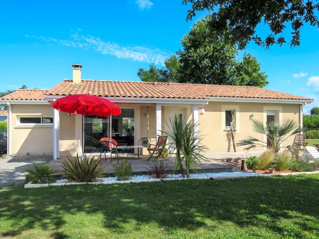 a house with a red umbrella in a yard at Holiday Home Mogador - CCP115 by Interhome in Carcans