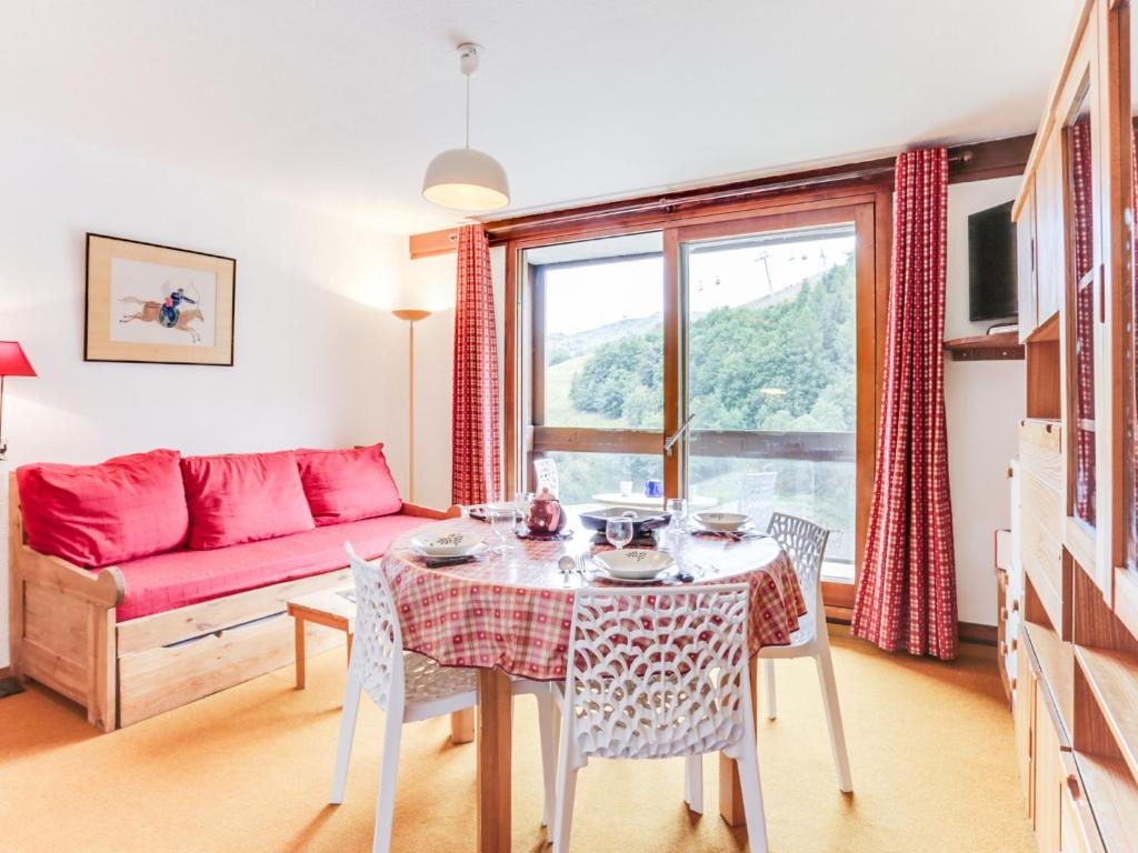 een woonkamer met een tafel en een rode bank bij Apartment Vostok Zodiaque-70 by Interhome in Le Corbier