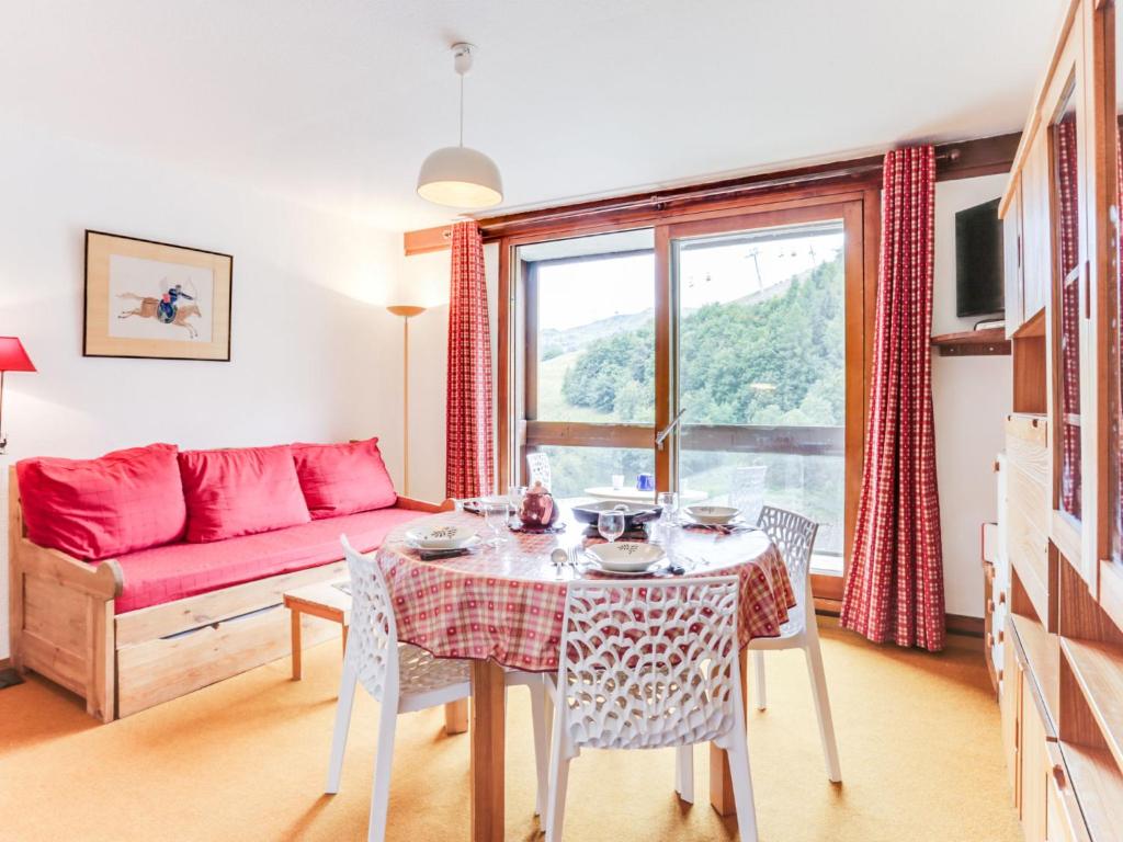 a living room with a table and a red couch at Apartment Vostok Zodiaque-70 by Interhome in Le Corbier