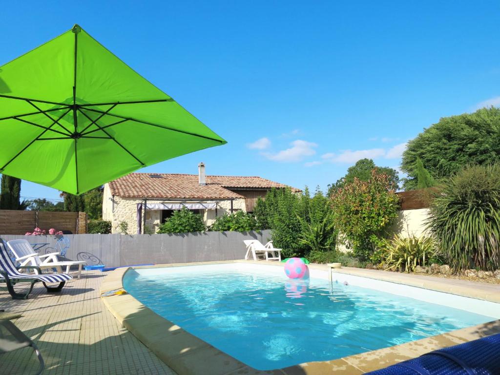 ein Pool mit einem grünen Regenschirm und einem Ball darin in der Unterkunft Holiday Home Tuilières - CME100 by Interhome in Cissac-Médoc