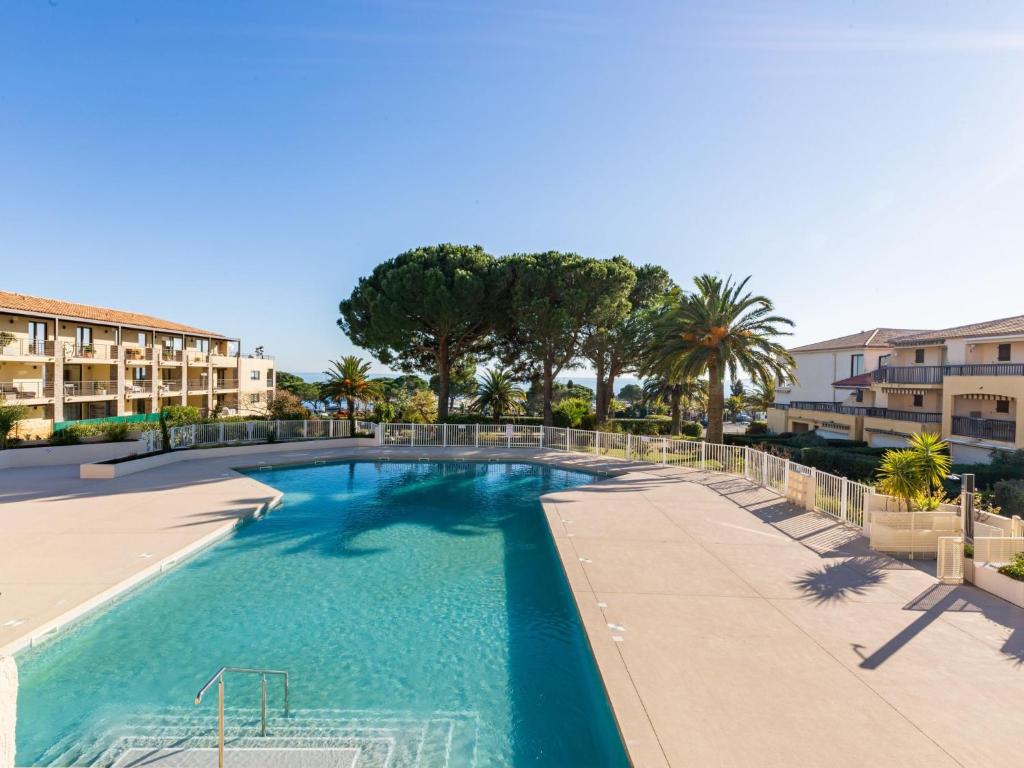 a large swimming pool with palm trees and buildings at Apartment Les Jardins d'Ys-8 by Interhome in Les Issambres