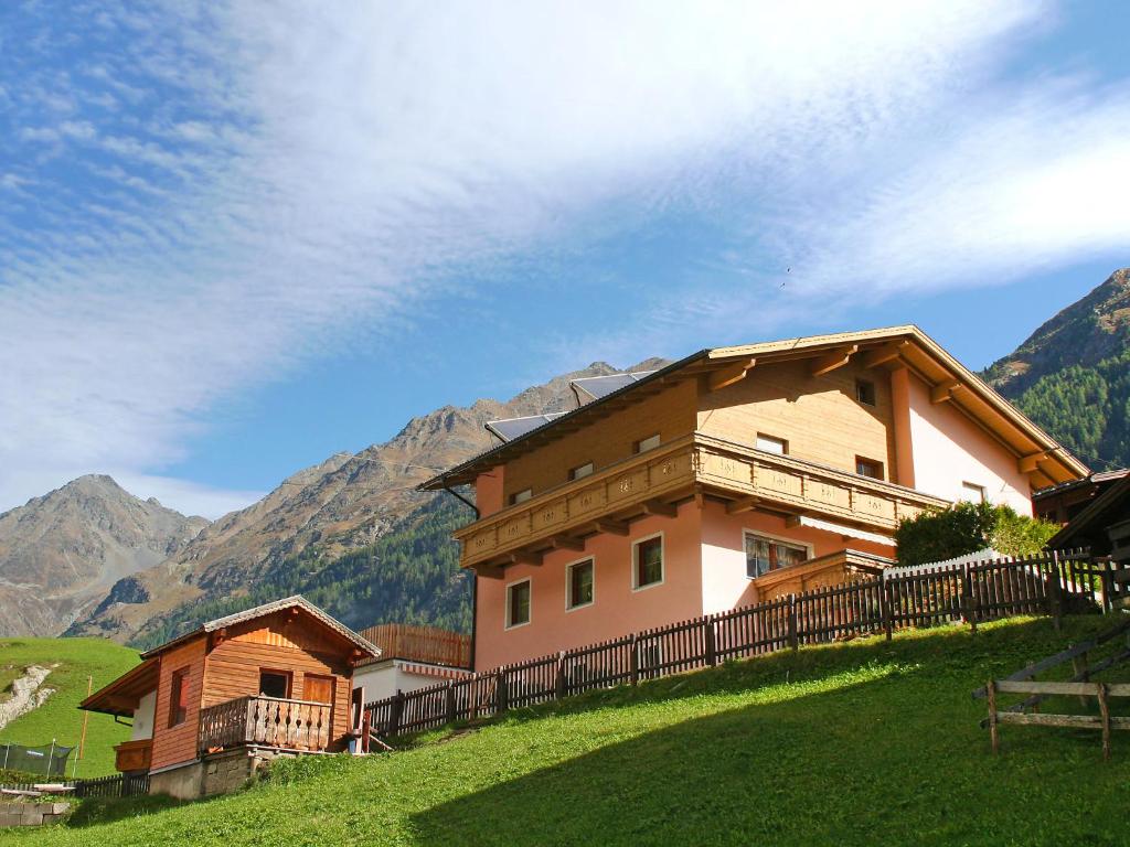 a house on a hill with mountains in the background at Apartment Mario in Sölden