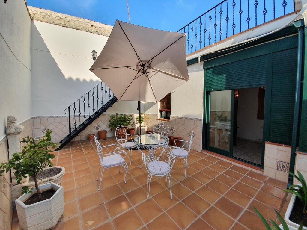 eine Terrasse mit einem Tisch, Stühlen und einem Sonnenschirm in der Unterkunft Casa La Plazuelilla in Chinchón