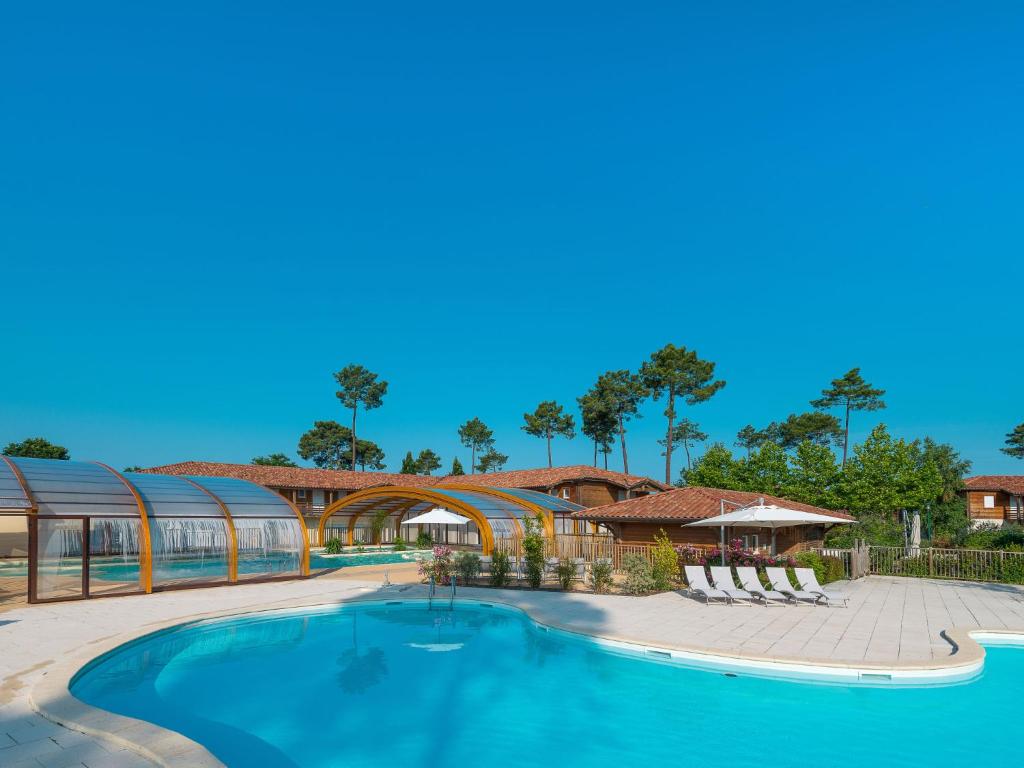 een zwembad in een resort met stoelen en een gebouw bij Apartment Les Cottages du Lac T2 by Interhome in Parentis-en-Born