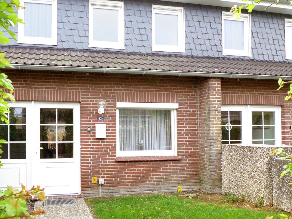 uma casa de tijolos com portas brancas e um quintal em Apartment Dehne-1 by Interhome em Norddeich