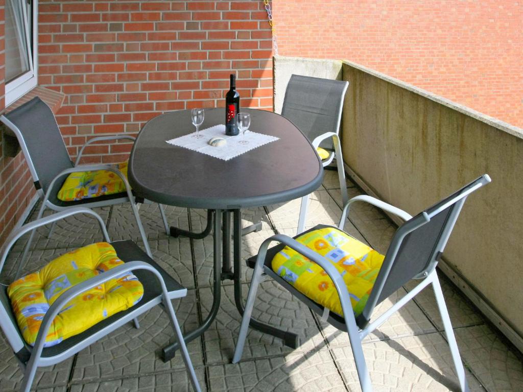 een tafel en stoelen op een patio met een fles wijn bij Apartment Norderney by Interhome in Dornumersiel