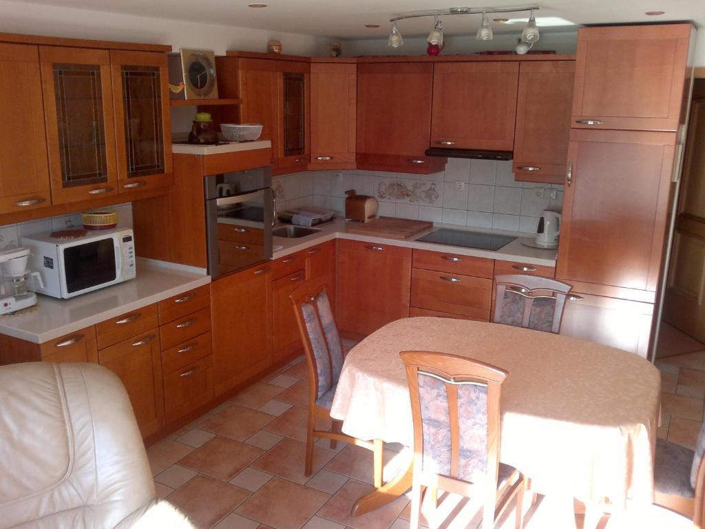 Apartment Kala في بونات: مطبخ بدولاب خشبي وطاولة مع كراسي