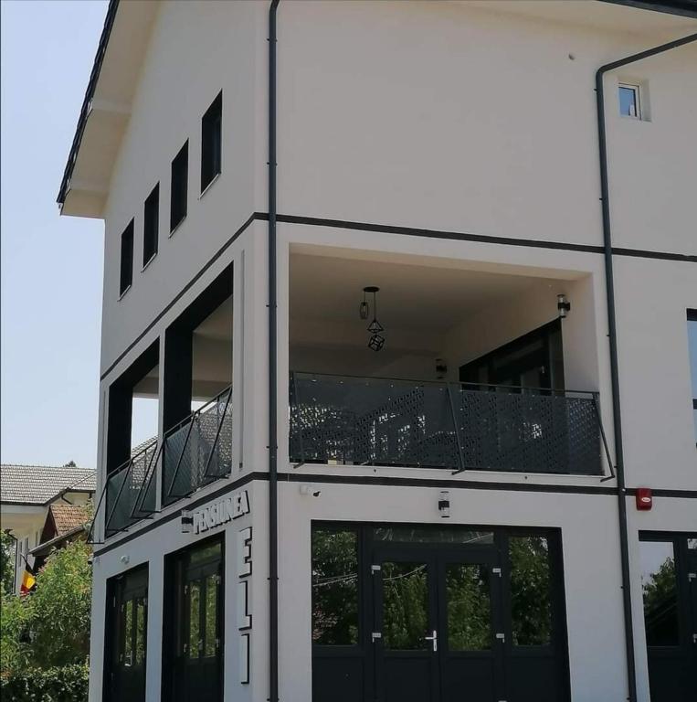 een wit gebouw met een balkon erboven bij Pensiunea Eli in Buziaş