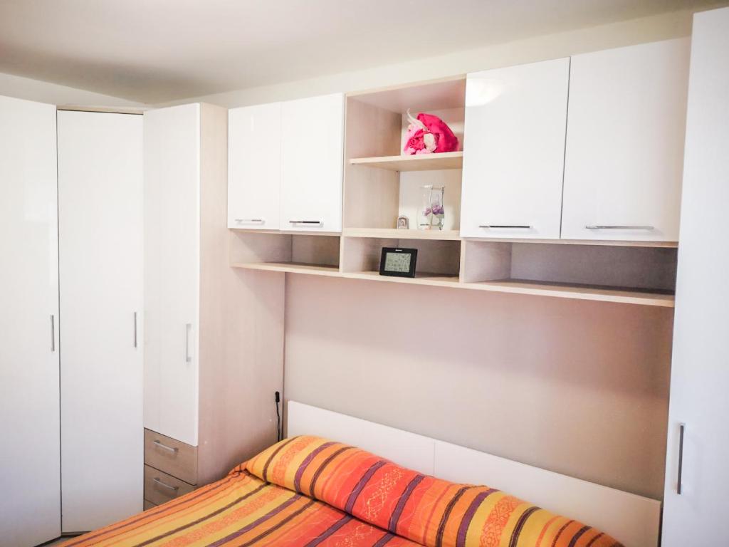 ein Schlafzimmer mit weißen Schränken und einem orangefarbenen Bett in der Unterkunft AriaDeMar in Koromačno