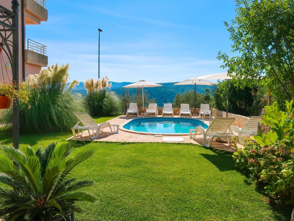 a backyard with a pool with chairs and umbrellas at Apartment Chantal-4 by Interhome in Rabac