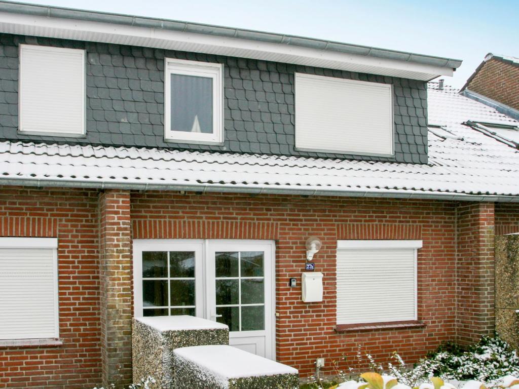 ein rotes Backsteinhaus mit weißen Fensterläden in der Unterkunft Apartment Fielapper by Interhome in Norddeich