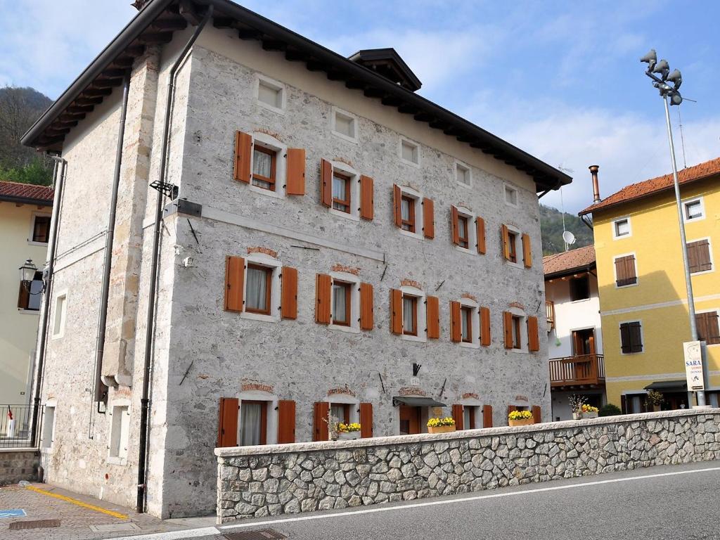 ein weißes Gebäude mit orangefarbenen Fensterläden auf einer Straße in der Unterkunft Apartment Albergo Diffuso - Cjasa Fantin by Interhome in Barcis