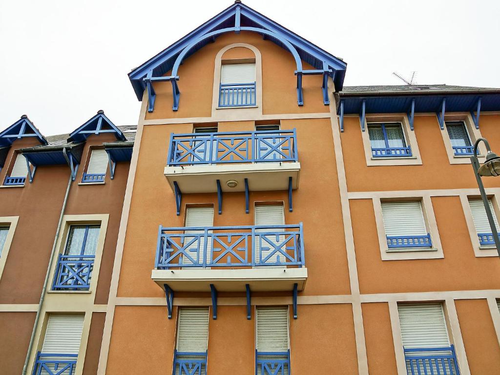 ディナールにあるStudio Appartement Aillerie by Interhomeの青いバルコニーが付いた高いオレンジ色の建物