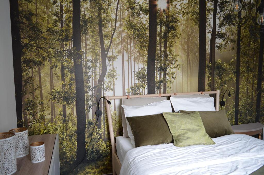 1 dormitorio con 1 cama en un mural del bosque en Le Salix, petite maison proche de Lille, entre ville et campagne, en Wavrin