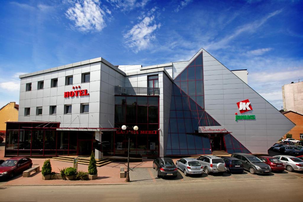 a building with cars parked in a parking lot at Hotel Janusz in Siedlce