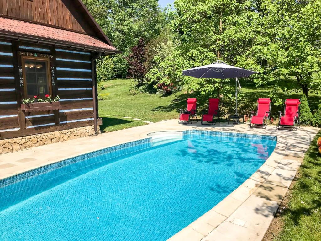a pool with chairs and an umbrella next to a house at Holiday Home Bastrówka by Interhome in Chrosna