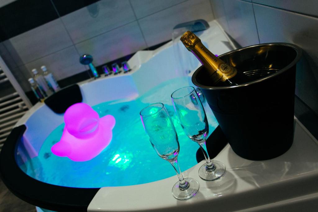 Una bañera con dos copas y una botella de champán. en Magnifique maison avec baignoire balnéo en Cornebarrieu