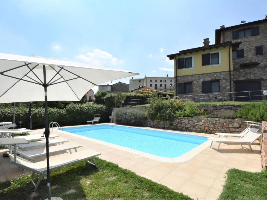 a swimming pool with an umbrella and lounge chairs next to it at Holiday Home La Corte Bricca - Casetta by Interhome in Castana