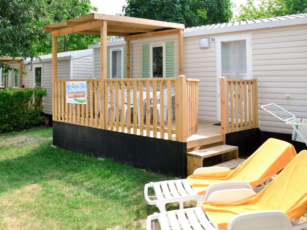 a cabin with a deck with chairs and a gazebo at Holiday Home Camping Laguna Village-1 by Interhome in Porto Falconera