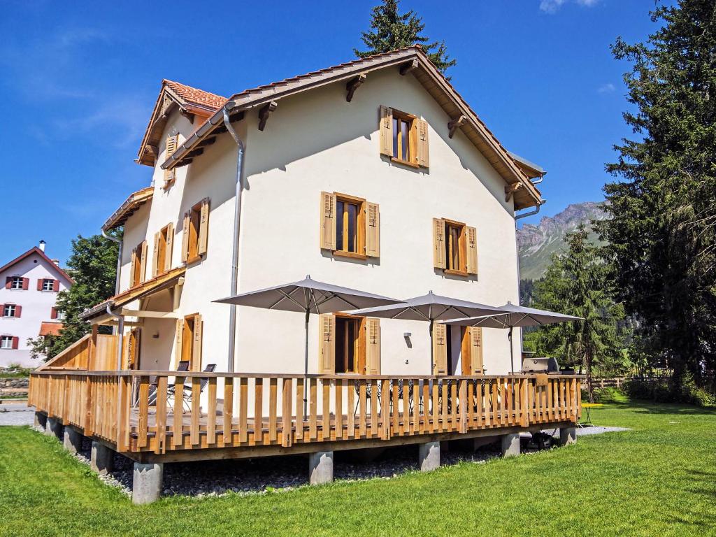 ein Haus mit einer Holzveranda und einem Sonnenschirm in der Unterkunft Holiday Home von Capeller by Interhome in Parpan