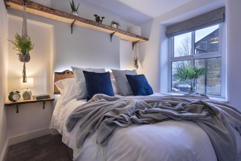 sypialnia z dużym łóżkiem z niebieskimi poduszkami i oknem w obiekcie Rosie's Escape with Hot Tub w mieście Barrowford