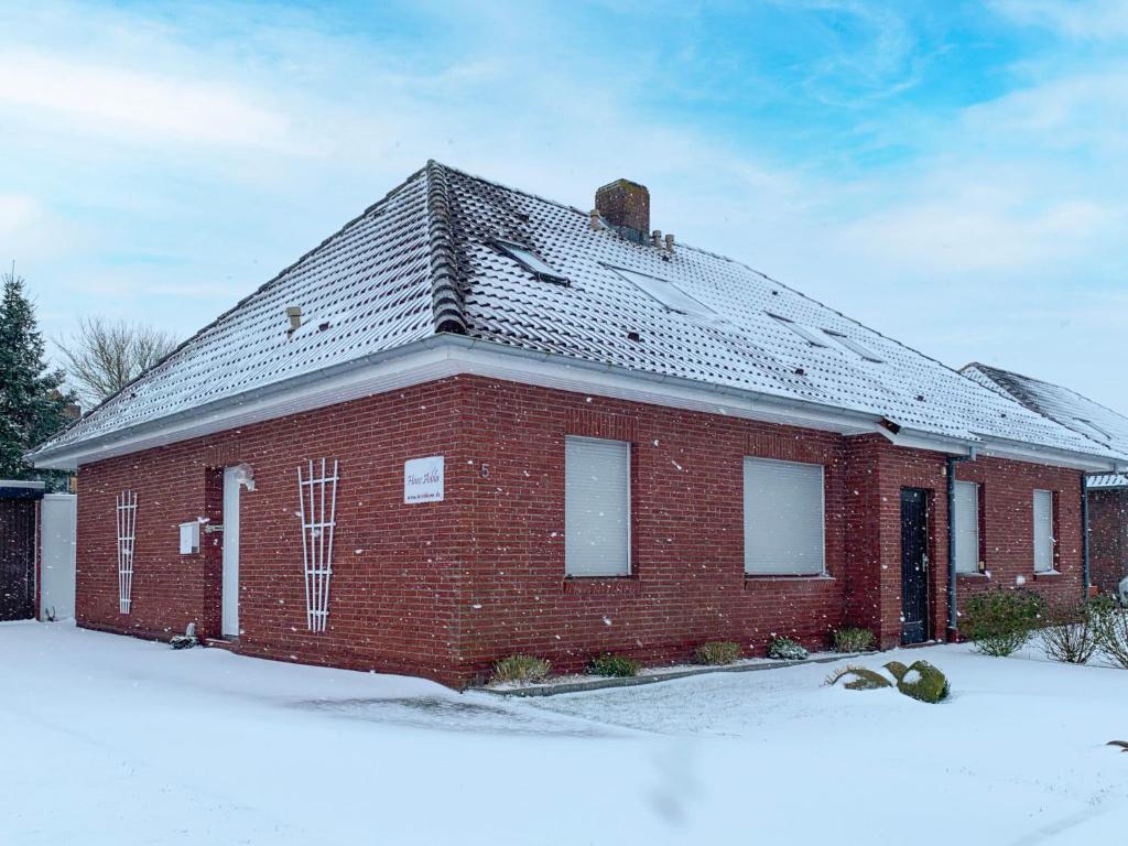 a red brick house with a roof in the snow at Holiday Home Adda by Interhome in Neßmersiel