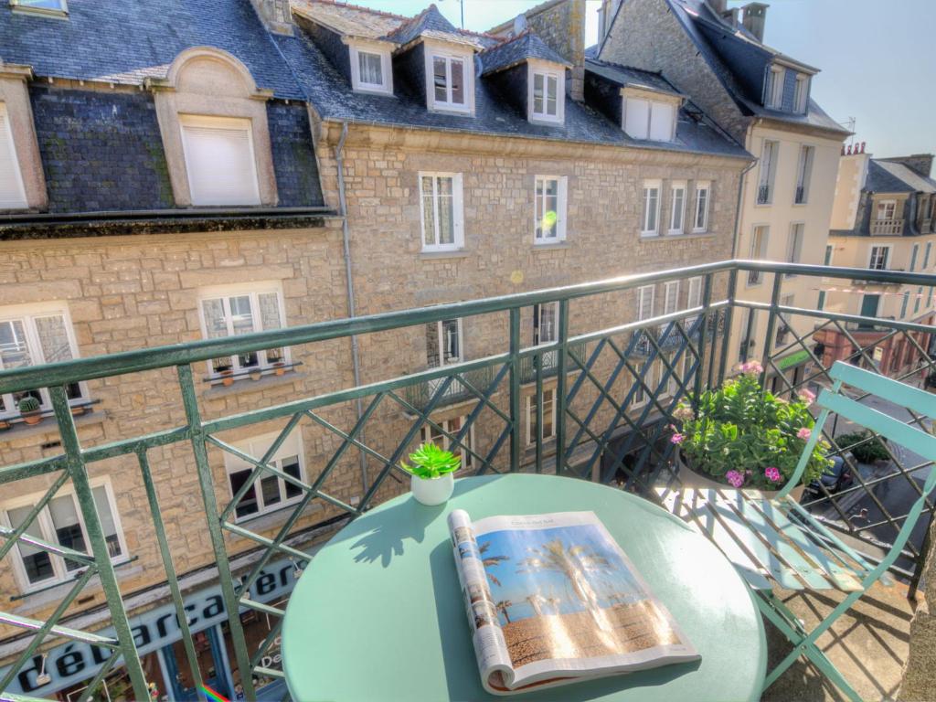 - une table avec un livre sur un balcon avec un bâtiment dans l'établissement Apartment L'Anse by Interhome, à Dinard