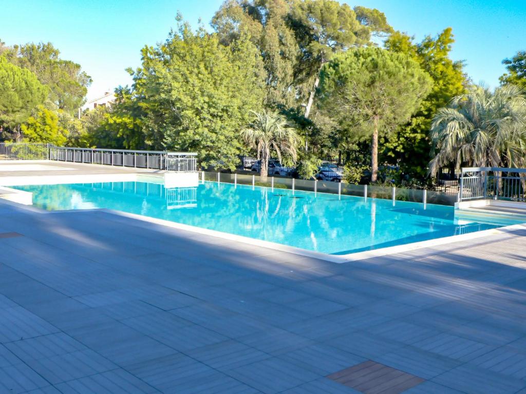 een zwembad met blauw water en bomen bij Apartment Le Grand Parc-6 by Interhome in Saint-Aygulf