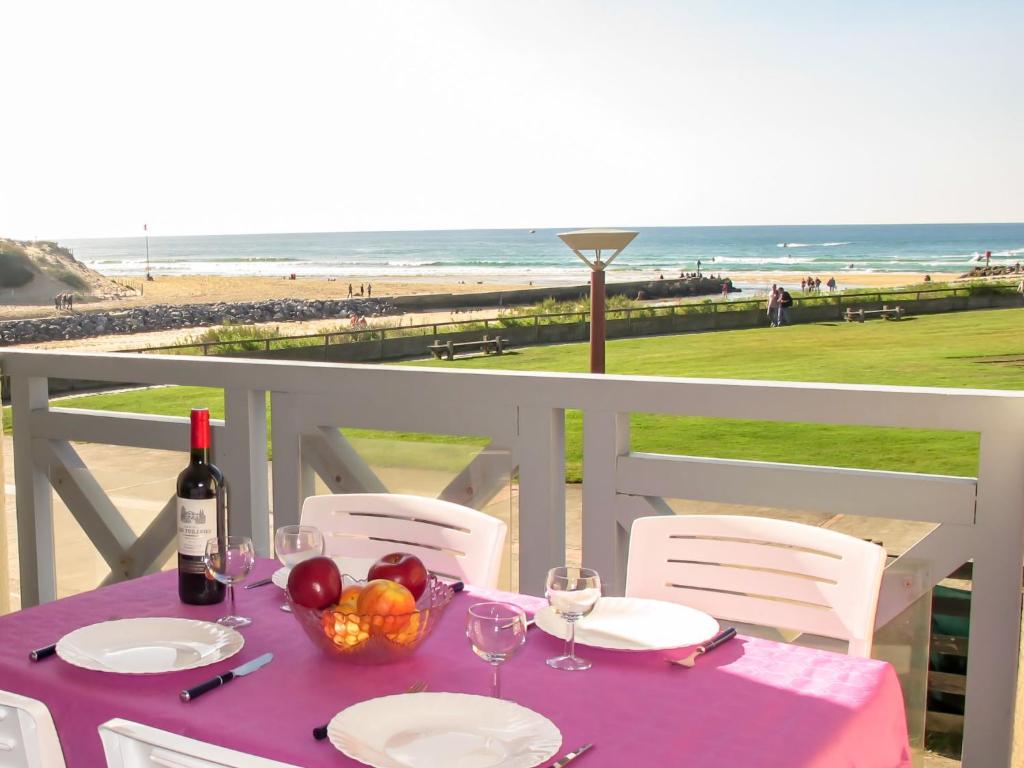 a table with a bowl of fruit and a bottle of wine at Apartment Grand Pavois-5 by Interhome in Mimizan-Plage