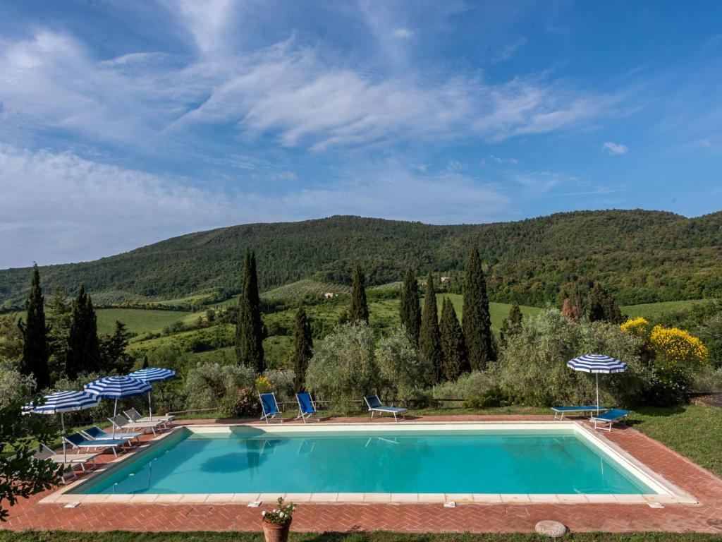 a swimming pool with chairs and a mountain in the background at Apartment Le Sodole - Petunia by Interhome in San Gimignano